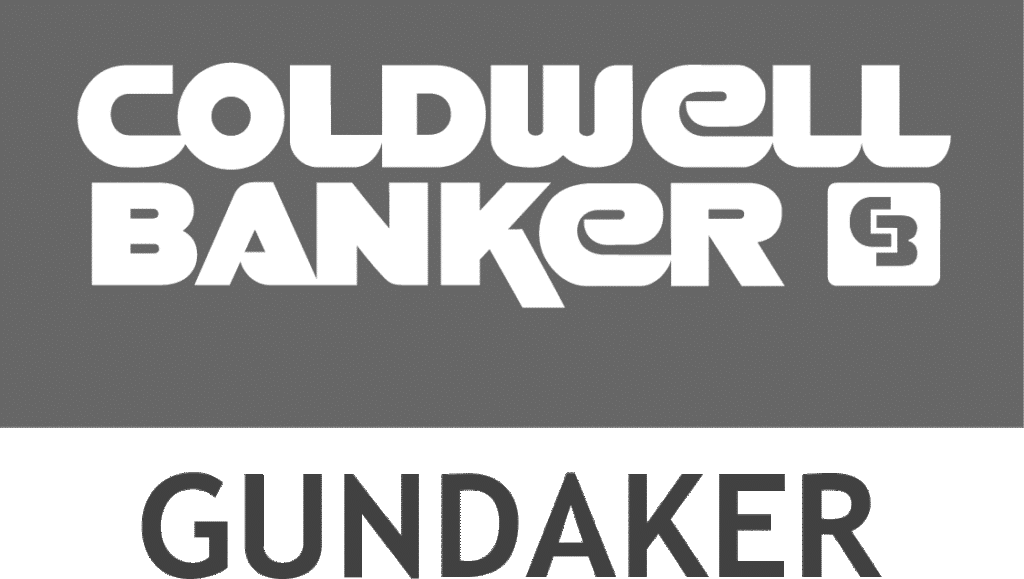 The image displays the logo of Coldwell Banker Gundaker, featuring bold white text on a gray background with a small emblem beside it.